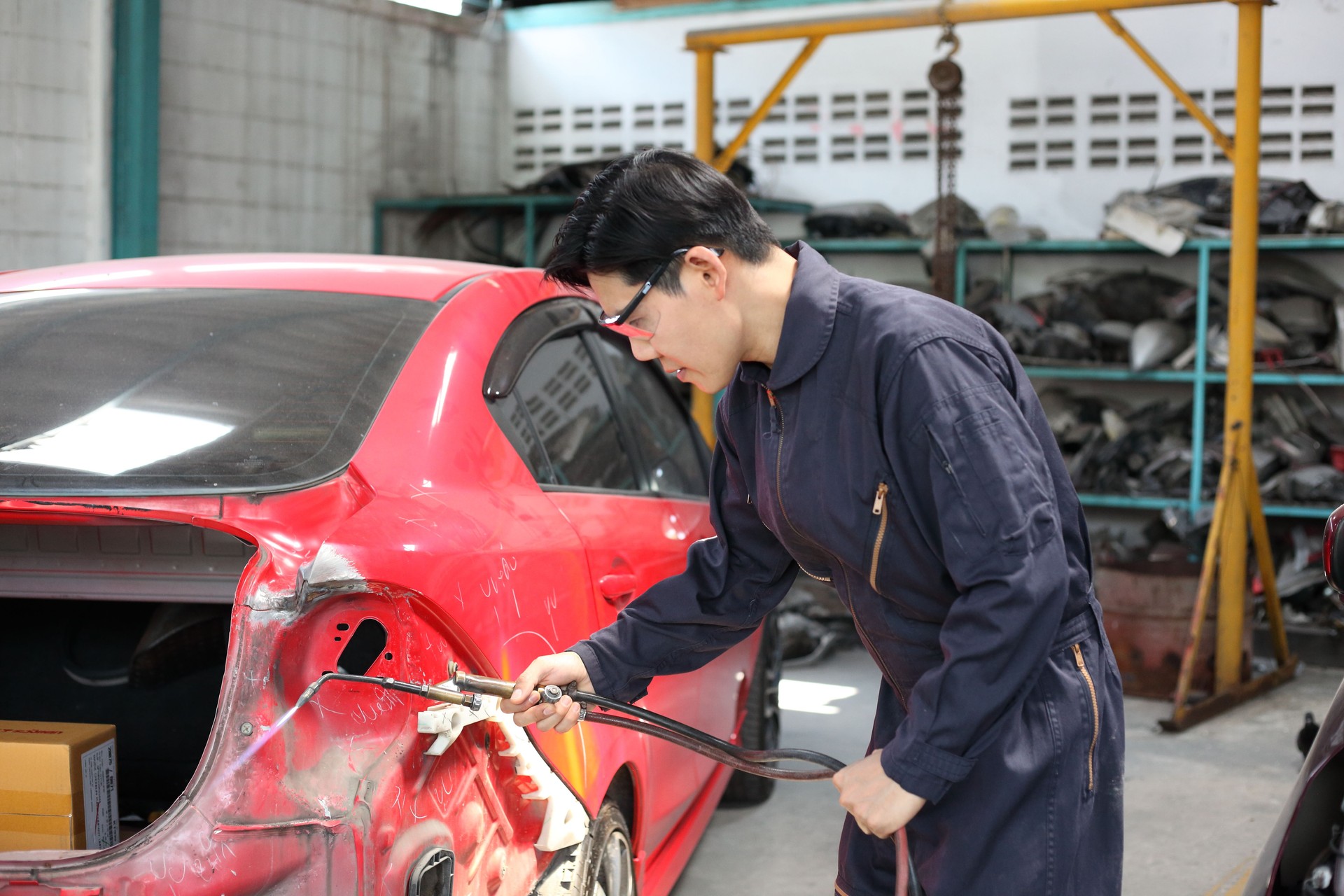 Auto mechanic working in garage. Repair service. Worker mechanics in uniform are working in auto service with lifted vehicle. Car repair maintenance.